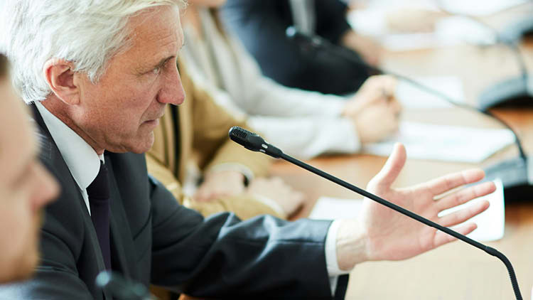 Man speaking into a microphone in a conference room.