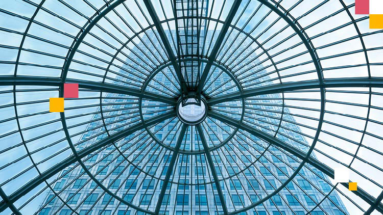 A photo of the inside of a glass dome with a steel frame with a tall building in the background.