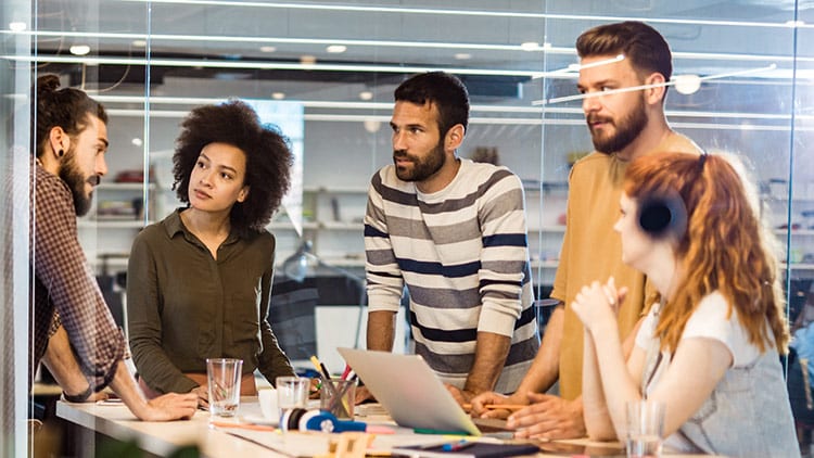 group of coworkers having a meeting around a laptop