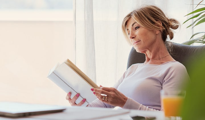 Man sitting on a sofa looking at a laptop and some documents