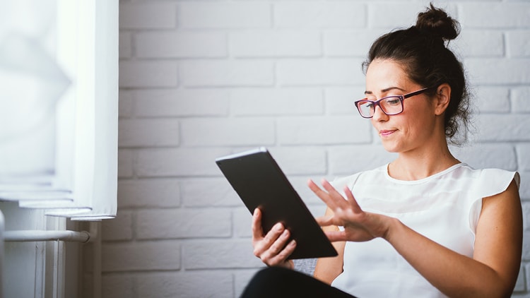 Woman, sitting and using a tablet