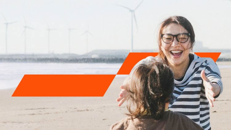 A woman about to hug a child on a beach