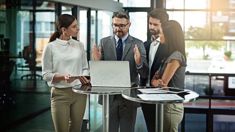 A group standing at a table around a laptop
