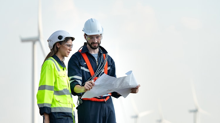 Workers looking at blueprints in a wind field