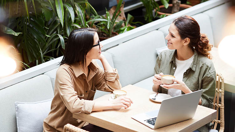 2 people talking in front of a laptop