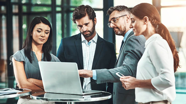 two men and two women looking at a laptop