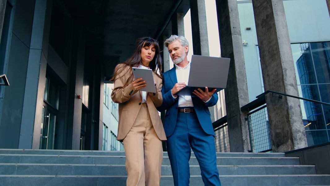 People talking while standing and looking at a laptop