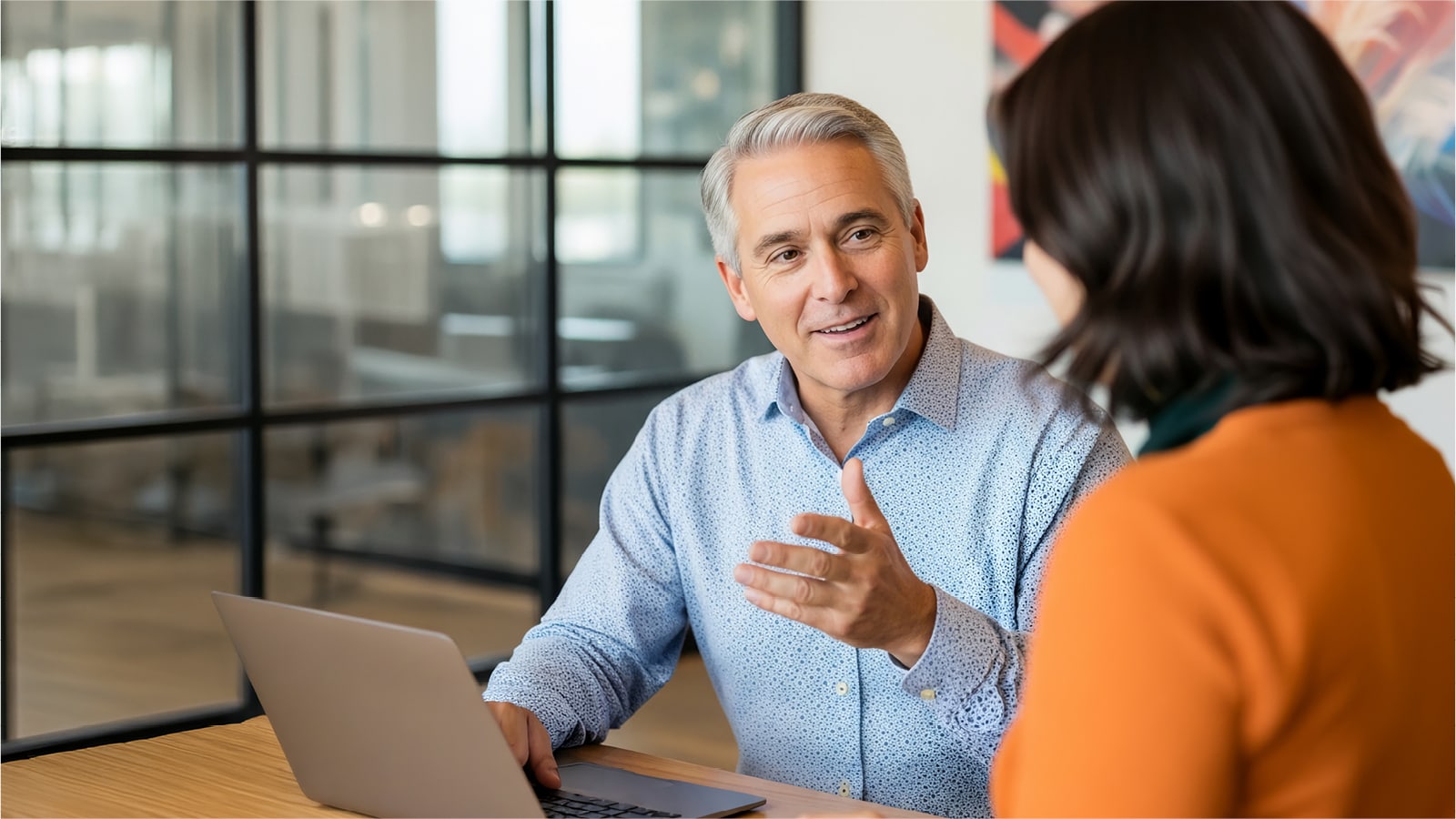  Two people talking while at a laptop